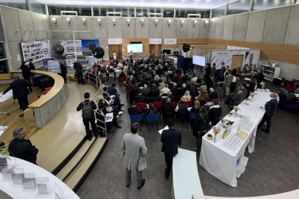 Forum territorial en salle d'hémicycle, public assis face à des panneaux d'exposition et stands d'information