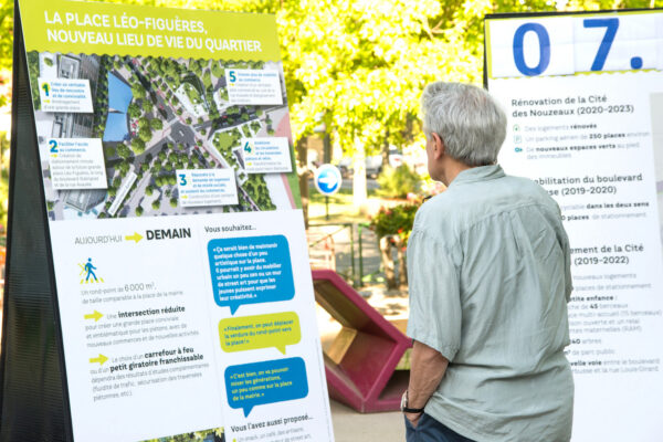 Habitant consultant un panneau d'exposition publique sur un projet de rénovation urbaine, en concertation de proximité